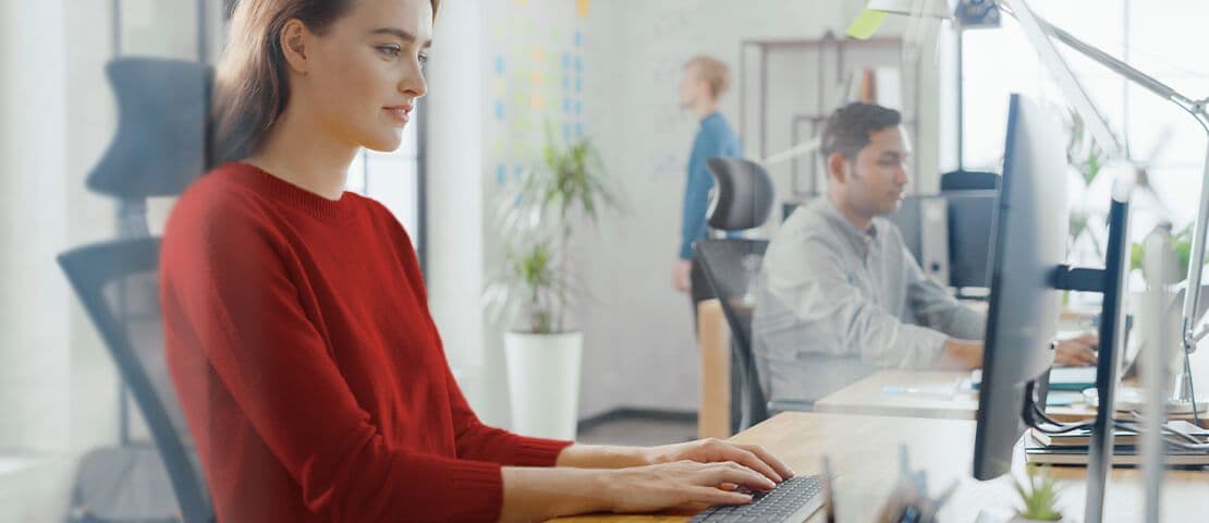 Mitarbeiter arbeiten an ergonomisch eingerichteten Büroarbeitsplätzen mit Monitoren und Bürostühlen