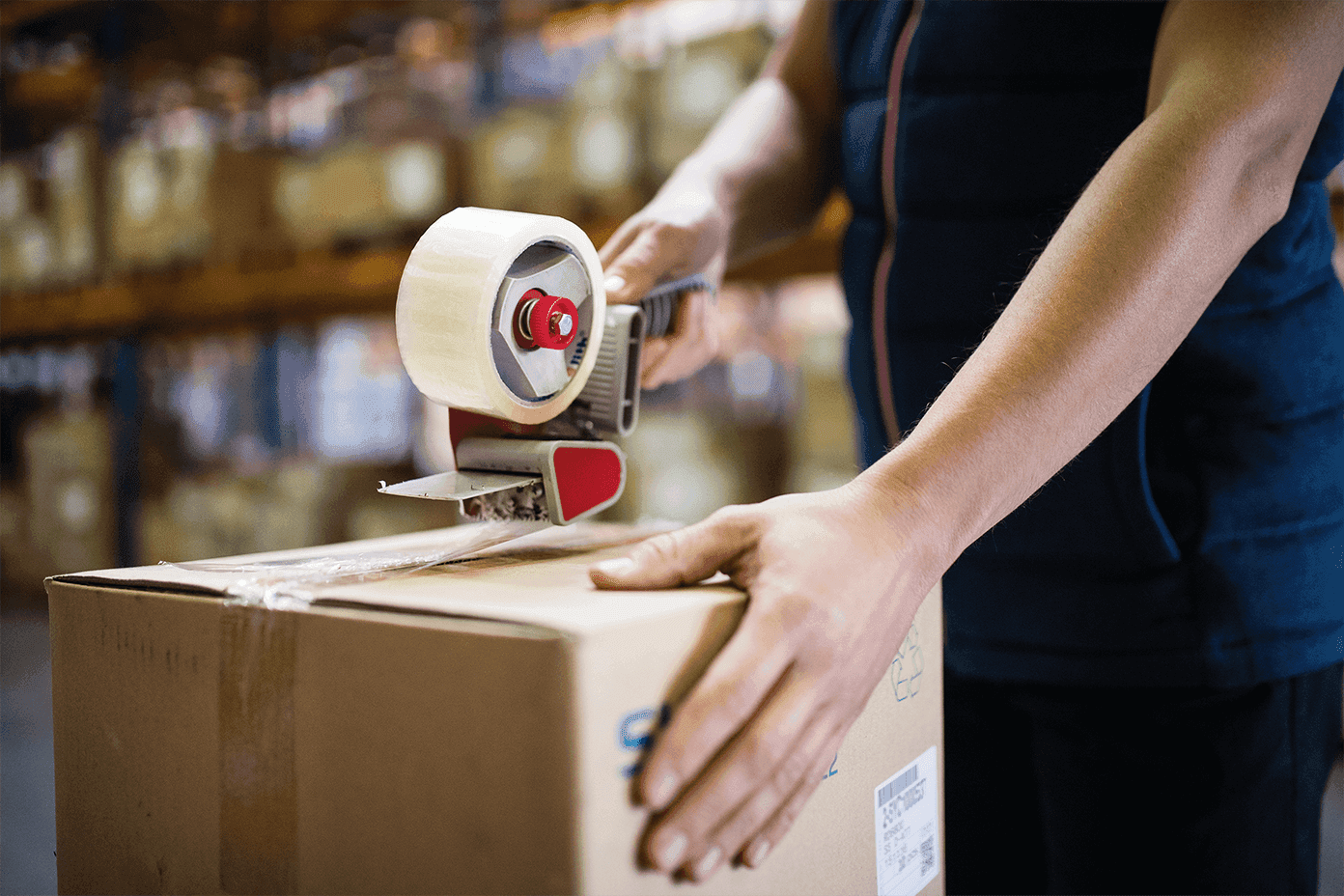 Paket wird mit Klebeband und Handabroller sicher verschlossen