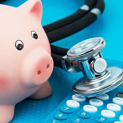 Sparschwein mit Stethoskop als Symbol für Kosten durch gesundheitliche Beschwerden im Büro